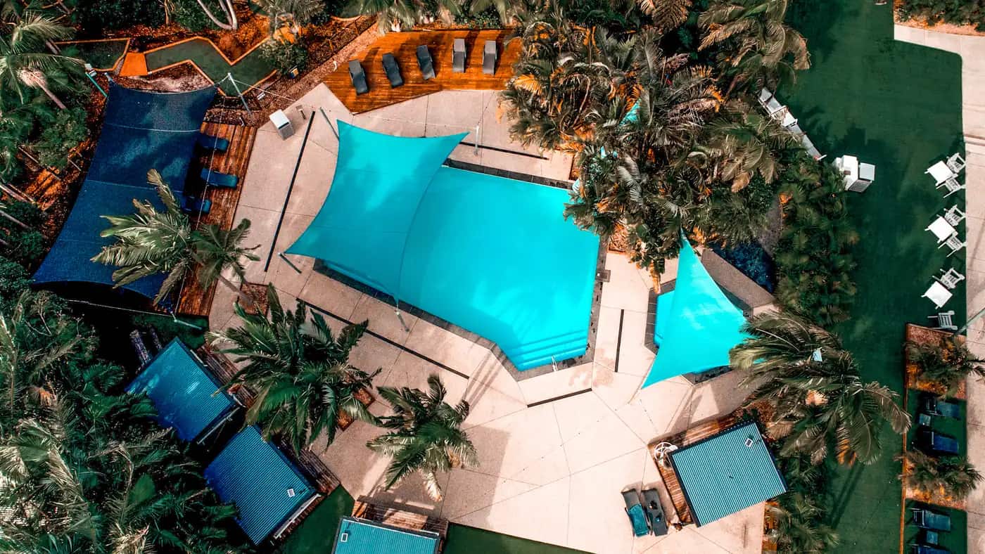 Aerial view over Solitary Islands Resort: rows of caravan and cabin sites beside the Wooli Wooli River, with the ocean and headland beyond.