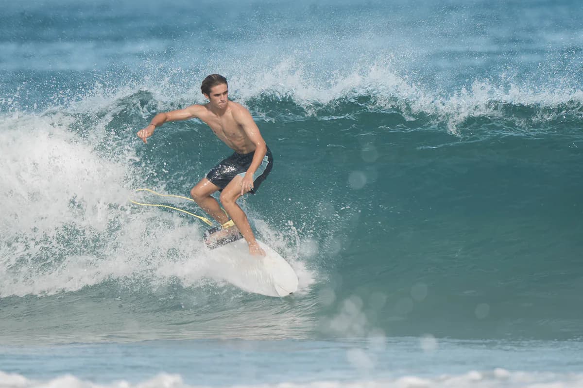 A surfer carving down the face of a clean green wave, spray flying off the back of the board.