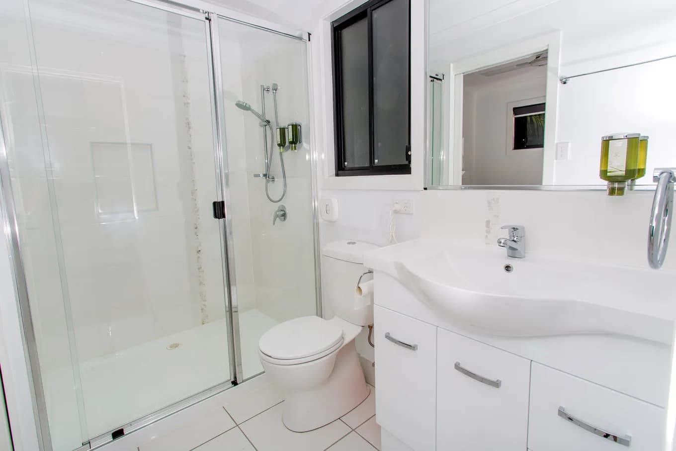 Bathroom in the executive cabin, with a sliding glass shower screen, a toilet and a white vanity with a mirror above.