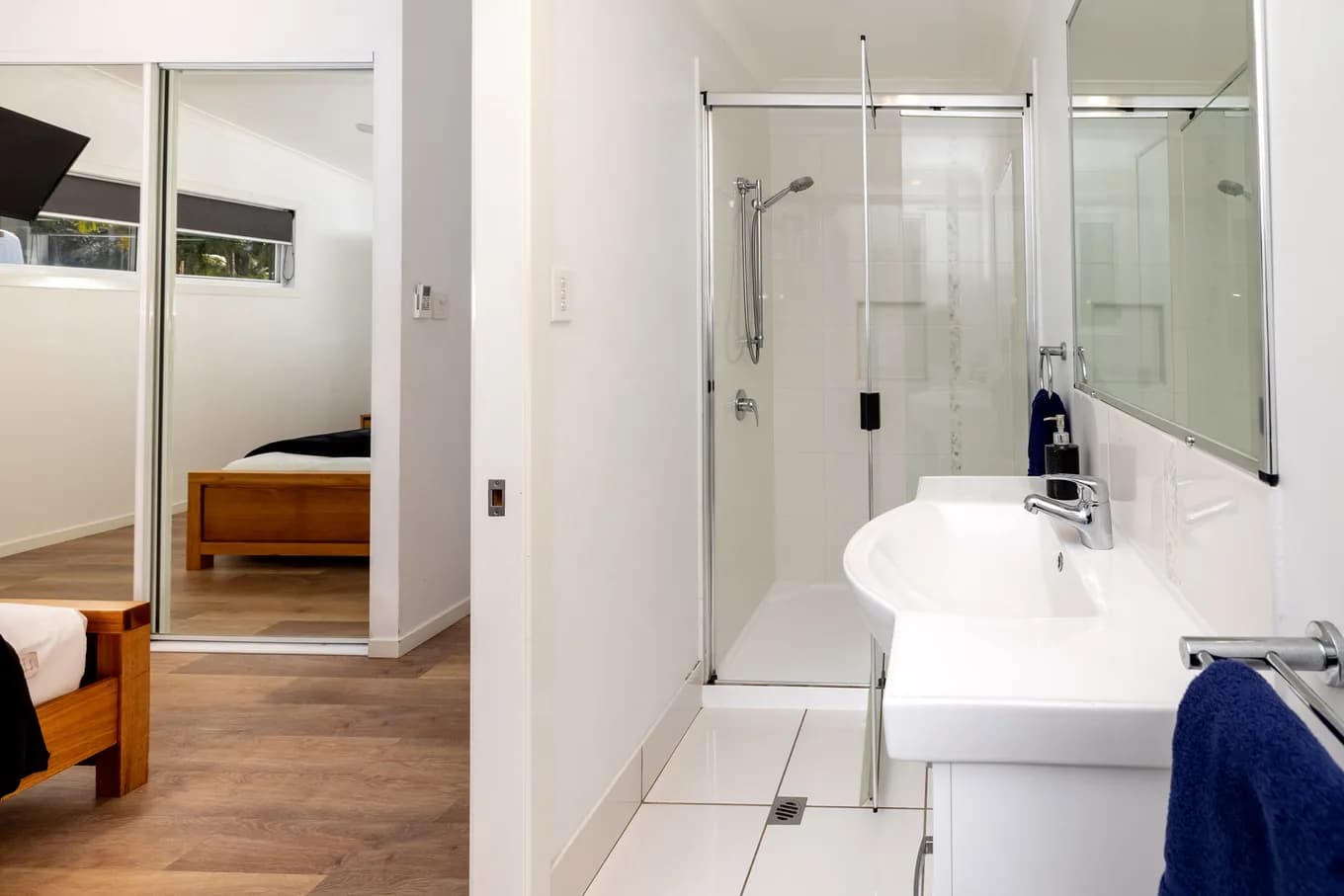 Ensuite in the three bedroom villa, with a glass shower recess, a white basin and a mirrored robe reflecting the bedroom beyond.