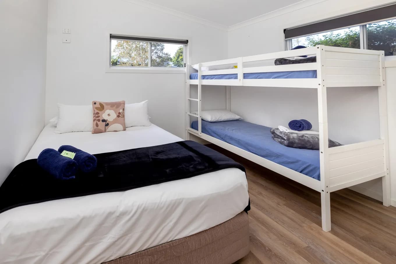 Second bedroom in the three bedroom villa, with a double bed made up in white beside a single bunk.